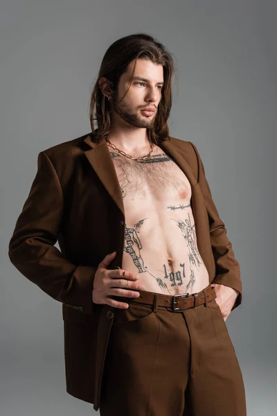 Shirtless and tattooed man in suit standing isolated on grey — Stockfoto