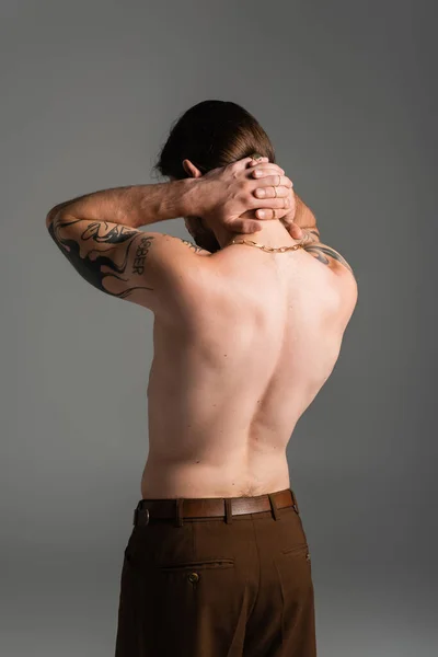 Shirtless and tattooed model touching neck isolated on grey — Photo de stock
