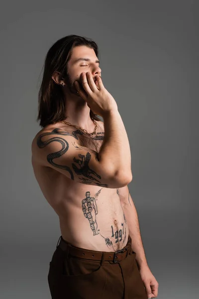 Long haired and tattooed model touching face isolated on grey - foto de stock