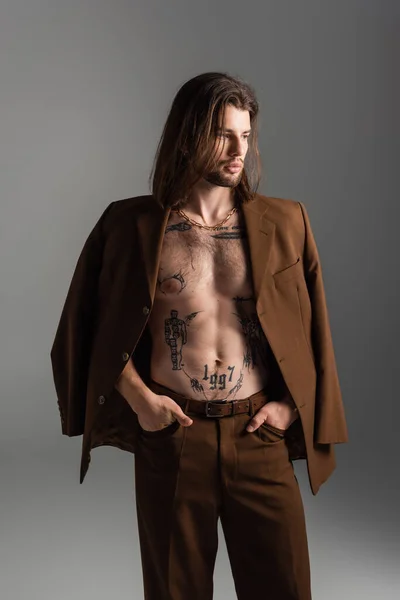 Stylish tattooed model posing in suit isolated on grey — Stock Photo