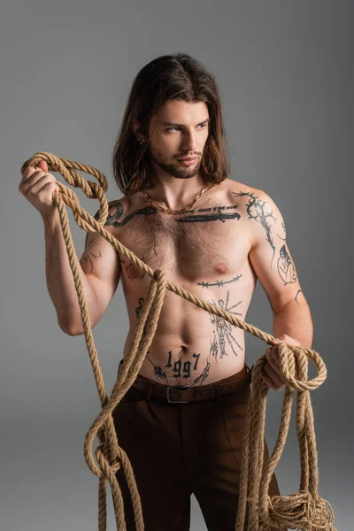 Sexy tattooed man holding rope isolated on grey — Stock Photo