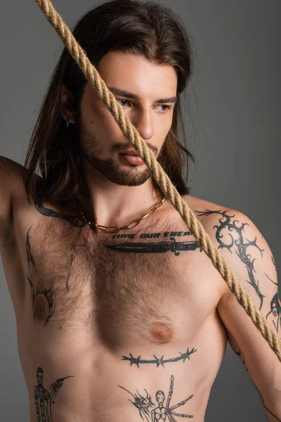 Shirtless tattooed man looking away near rope isolated on grey — Photo de stock