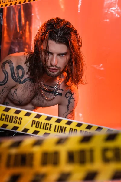 Long haired tattooed man looking at camera near police line - foto de stock