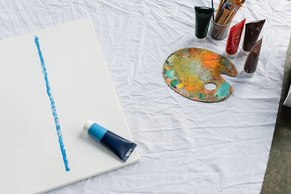Top view of paint tube and painting on cloth in studio - foto de stock