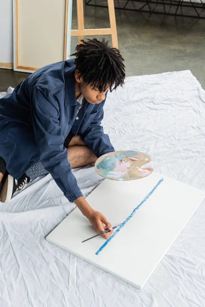 High angle view of young african american artist painting on canvas in workshop — Stock Photo