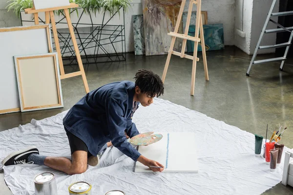 Artiste afro-américain avec peinture de palette sur toile en atelier — Photo de stock