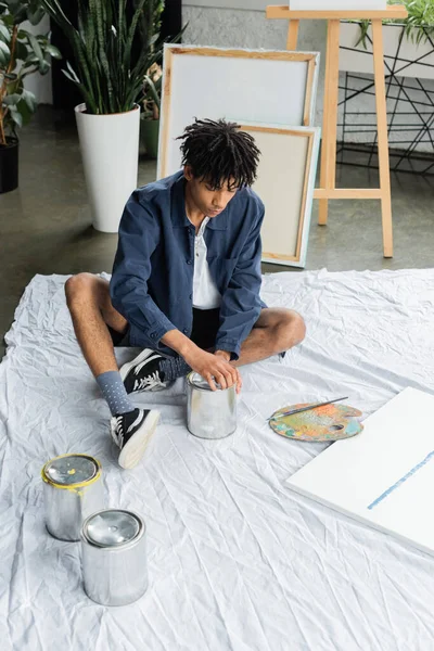 Junge afrikanisch-amerikanische Künstlerin öffnet Glas mit Farbe auf Werkstatt — Stockfoto