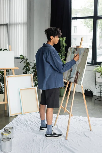Side view of african american artist painting on canvas in workshop — Stock Photo