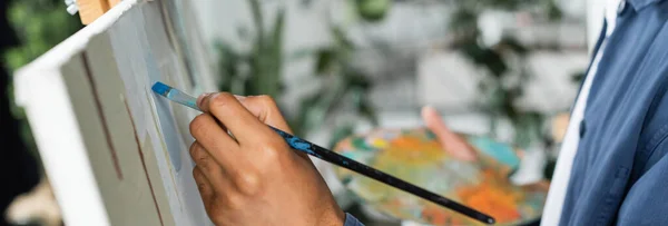 Cropped view of african american man painting on canvas in studio, banner — Stock Photo