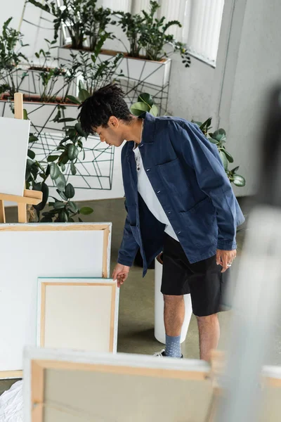 Side view of african american artist taking canvas in studio — Stock Photo