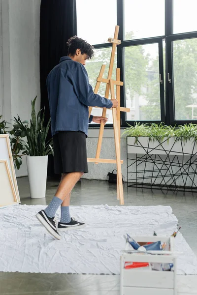 Side view of african american artist holding easel in studio — Stock Photo