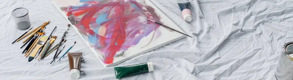 High angle view of paintbrushes near paints and drawing on cloth, banner — Stock Photo