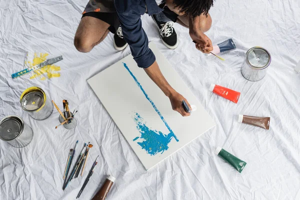 Top view of african american artist pouring paint on canvas in studio — Stock Photo