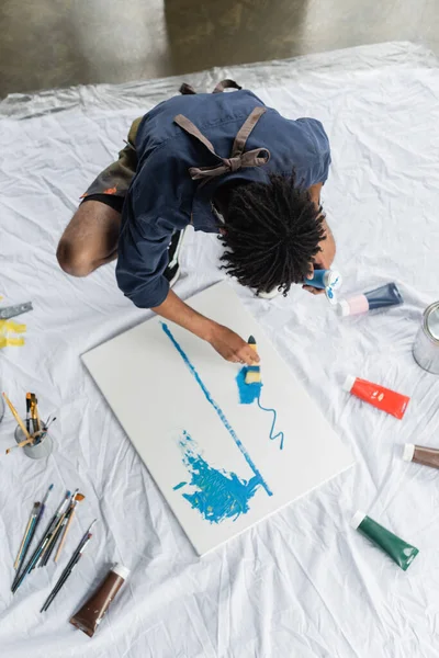 Veduta aerea dell'artista afro-americano che dipinge su tela su pavimento in studio — Foto stock
