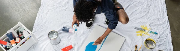 Overhead view of african american artist painting on canvas on floor in workshop, banner — Stock Photo