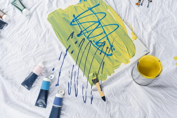 Top view of drawing near tubes with paints on cloth on floor - foto de stock
