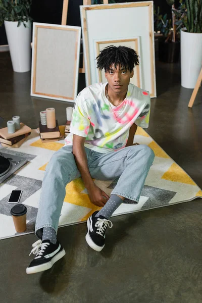 African american artist sitting near coffee and smartphone in art studio — Stock Photo