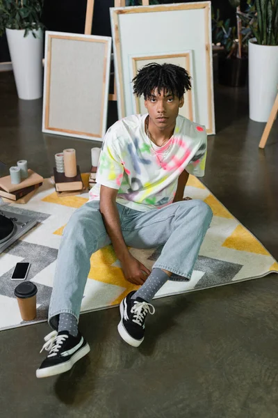 African american artist sitting near coffee and smartphone in art studio — Fotografia de Stock