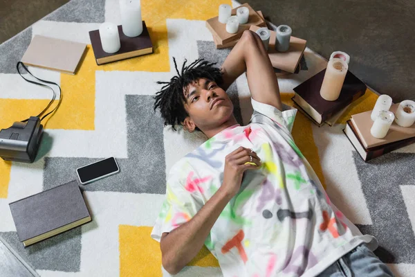 Top view of african american artist lying near books and candles in workshop — Photo de stock