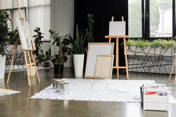 Jars with paints on cloth near canvases in studio — Stock Photo