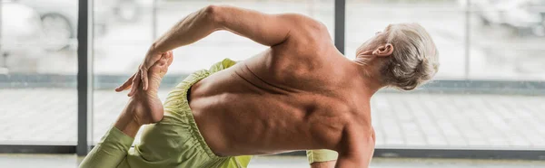 Grauhaariger Mann in Rückenlage beim Yoga, während er sich im Studio zurückstreckt, Banner — Stockfoto