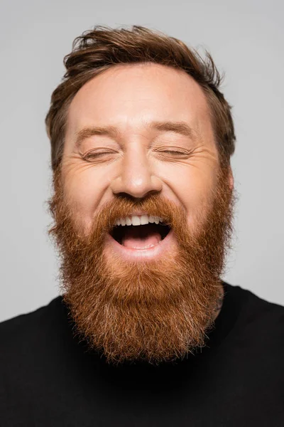 Portrait d'un homme barbu excité riant les yeux fermés isolés sur le gris — Photo de stock