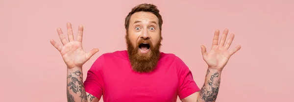 Astonished bearded man with open mouth showing wow gesture isolated on pink, banner — Foto stock