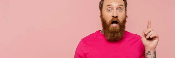 Amazed bearded man in bright magenta t-shirt showing idea sign isolated on pink, banner — Stock Photo