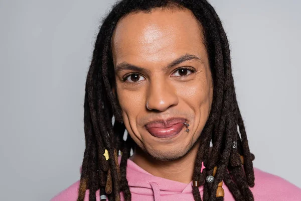 Portrait of cheerful multiracial man in pink hoodie looking at camera isolated on gray — Fotografia de Stock
