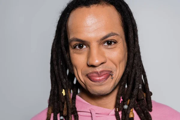 Portrait de l'homme multiracial joyeux en sweat à capuche rose regardant la caméra isolée sur gris — Photo de stock