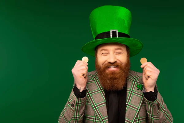Cheerful bearded man in hat holding coins during saint patrick celebration isolated on green — Photo de stock