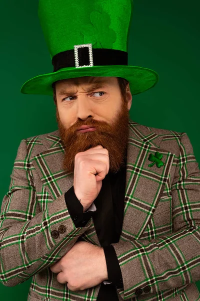 Бородатий чоловік в капелюсі з конюшиною дивиться ізольовано на зеленому — стокове фото