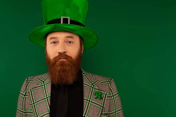 Portrait of bearded man in hat with clover looking at camera isolated on green — Stock Photo
