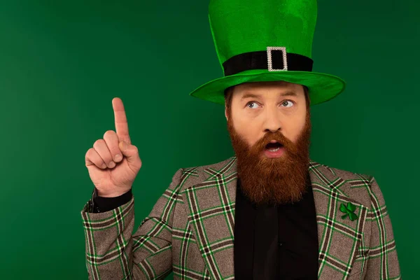 Задумчивый бородатый мужчина в шляпе с клевером, идея изолирована на зеленый — стоковое фото