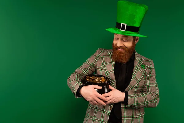 Lächelnder bärtiger Mann mit Hut, Topf mit Münzen auf grünem Grund — Stockfoto