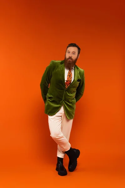 Full length of stylish man in velour jacket posing on red background — Stock Photo