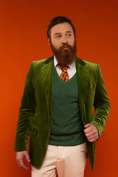 Stilvoller Mann in grüner Jacke posiert auf rotem Hintergrund — Stockfoto
