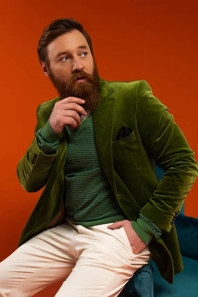 Portrait of fashionable model posing near blue armchair on red background - foto de stock