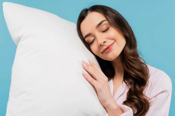 Morena mujer joven con los ojos cerrados acostado en la almohada blanca aislado en azul - foto de stock