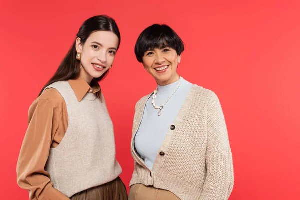 Happy asian mother and daughter in stylish casual clothes smiling at camera isolated on coral — Stock Photo
