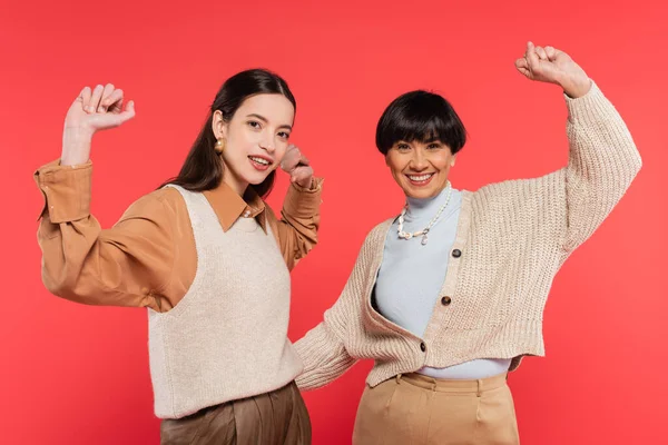 Excited asian mother and daughter in trendy clothes showing win gesture isolated on coral — Foto stock