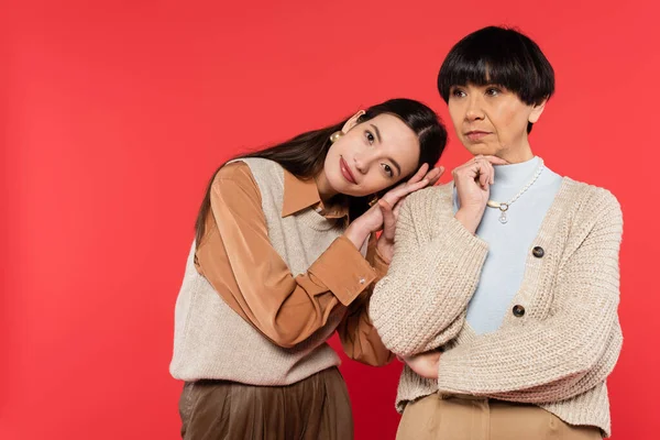 Young asian woman leaning on shoulder of mother isolated on coral — Stock Photo