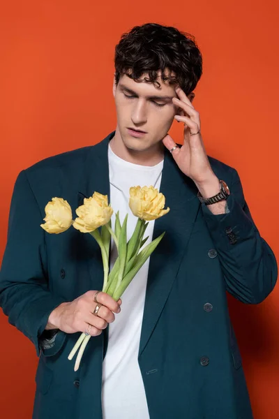 Trendy model in jacket holding tulips on red background — Stock Photo