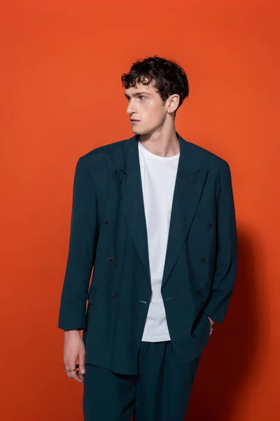 Stylish young man in blue suit posing on red background — Foto stock