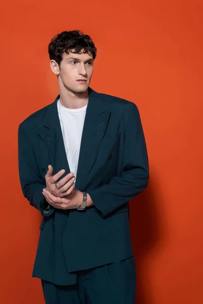 Brunette man in stylish blue suit posing on red background — Stock Photo
