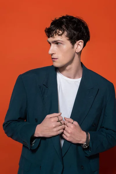 Curly homem ajustando elegante blazer azul no fundo vermelho — Fotografia de Stock
