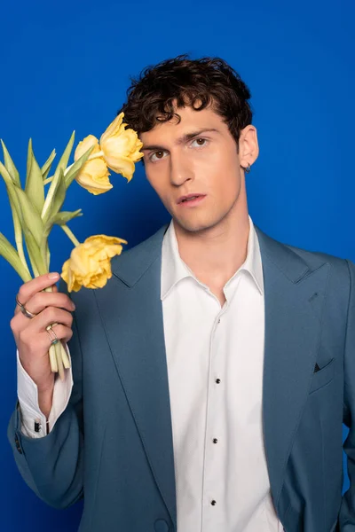 Uomo riccio in giacca e camicia con tulipani su sfondo blu — Foto stock