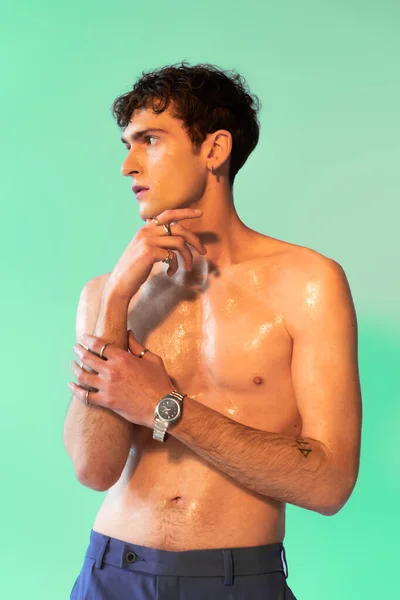 Shirtless man with fingerings and oil on body posing on green background - foto de stock