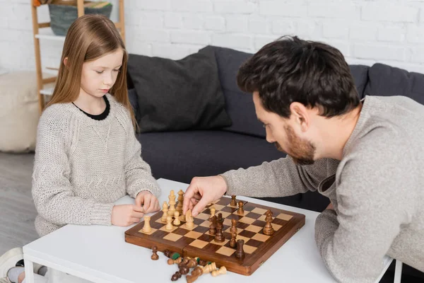 Figure de déménagement père barbu tout en jouant aux échecs avec fille préadolescente dans le salon — Photo de stock