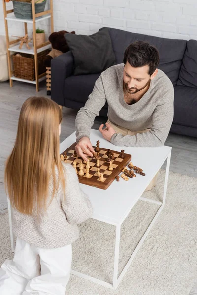 Blick aus der Vogelperspektive auf einen bärtigen Mann, der zu Hause mit seiner Tochter Schach spielt — Stockfoto